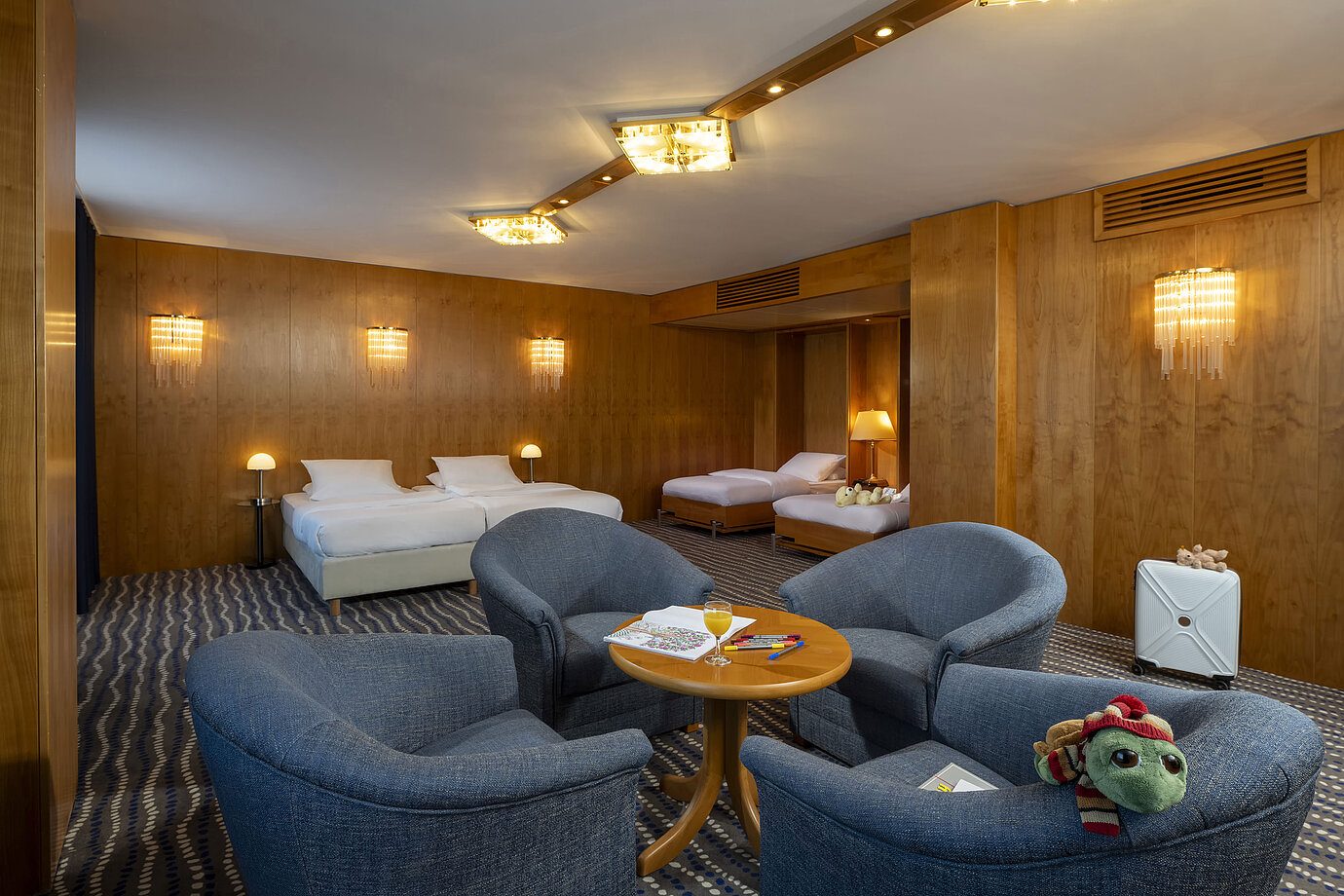Chambre familiale supérieure spacieuse au Maritim Hotel Magdeburg avec deux lits doubles, coin salon et détails adaptés aux enfants.