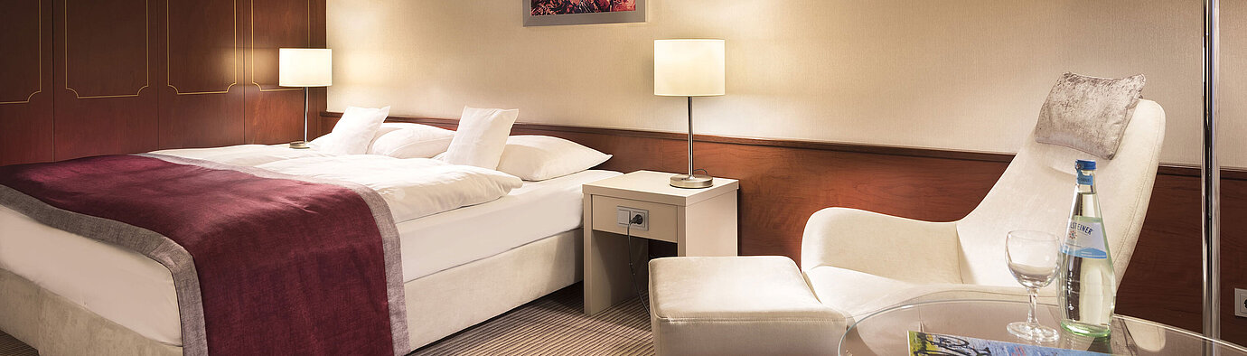 Classic room  Classic room at Maritim Hotel Bonn, comfortably furnished with double bed, armchair, table, and modern lighting.