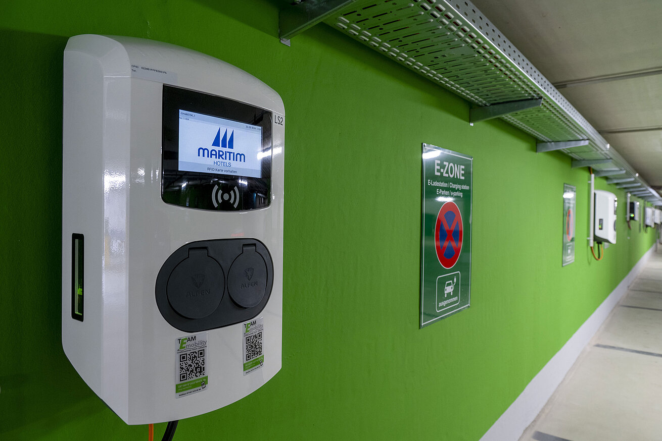 Close-up of an electric vehicle charging station with the Maritim Hotels logo in the E-Zone of the parking garage.