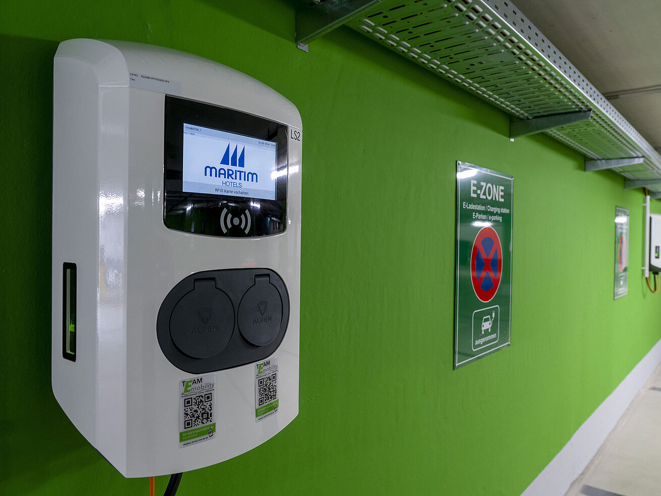 Close-up of an electric vehicle charging station with the Maritim Hotels logo in the E-Zone of the parking garage.