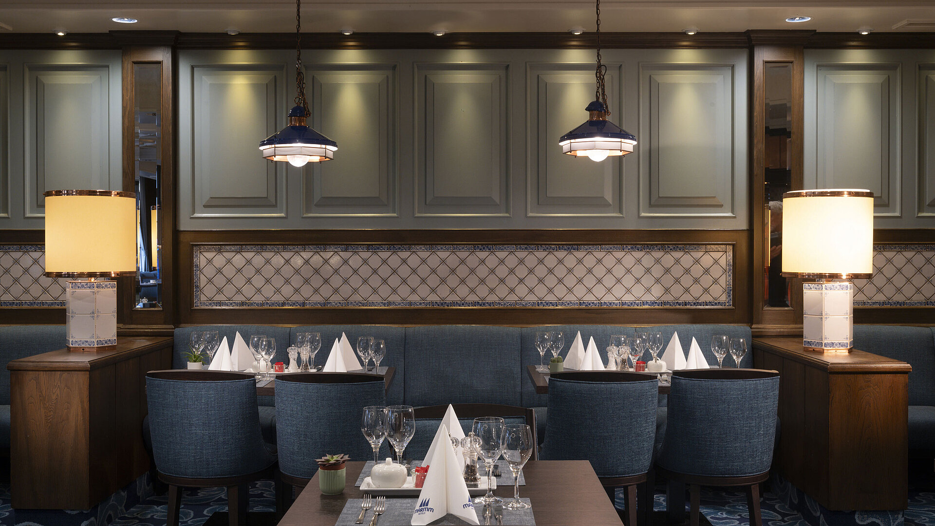Elegant restaurant at the Maritim Hotel Darmstadt with set tables, stylish lamps, and a cozy atmosphere.