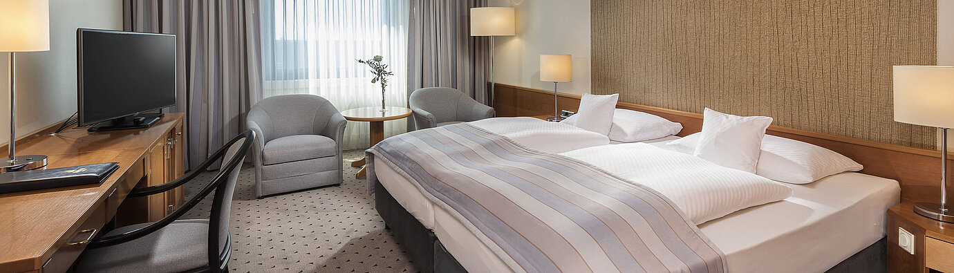 Camera doppia Classic moderna con letto matrimoniale accogliente, area salotto e scrivania al Maritim Hotel Hannover.