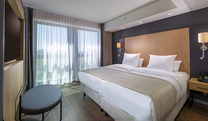 Chambre double spacieuse avec design moderne, lits confortables et vue sur la ville au Maritim Hotel Ingolstadt.