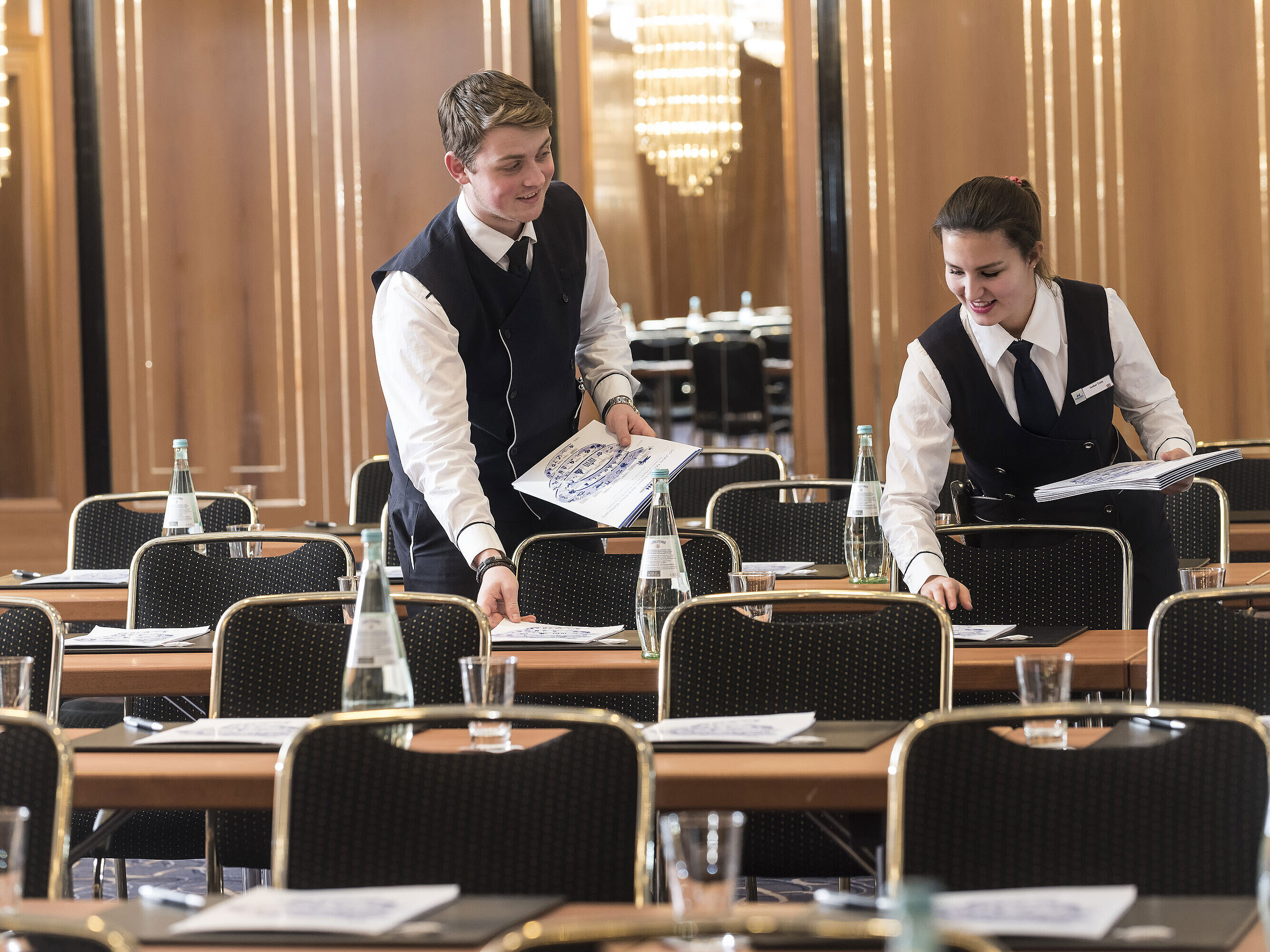 Dos empleados colocan documentos en mesas de reuniones en el Maritim Hotel Stuttgart