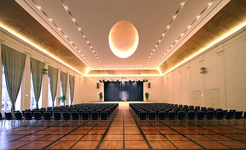 Salón de banquetes elegante en Maritim Hotel Fulda con escenario, iluminación sofisticada y asientos para eventos.