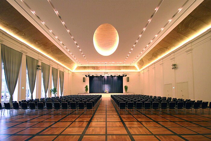 Salón de banquetes elegante en Maritim Hotel Fulda con escenario, iluminación sofisticada y asientos para eventos.