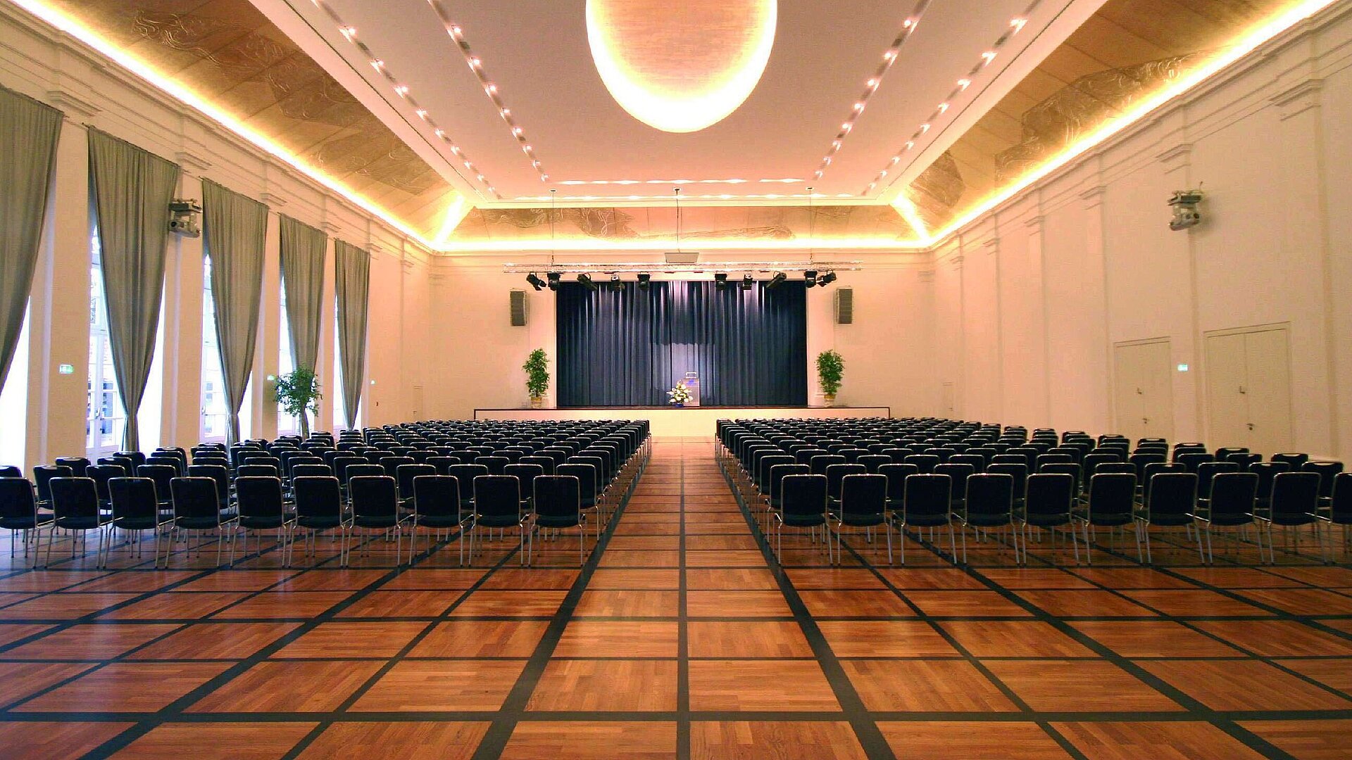 Salón de banquetes elegante en Maritim Hotel Fulda con escenario, iluminación sofisticada y asientos para eventos.