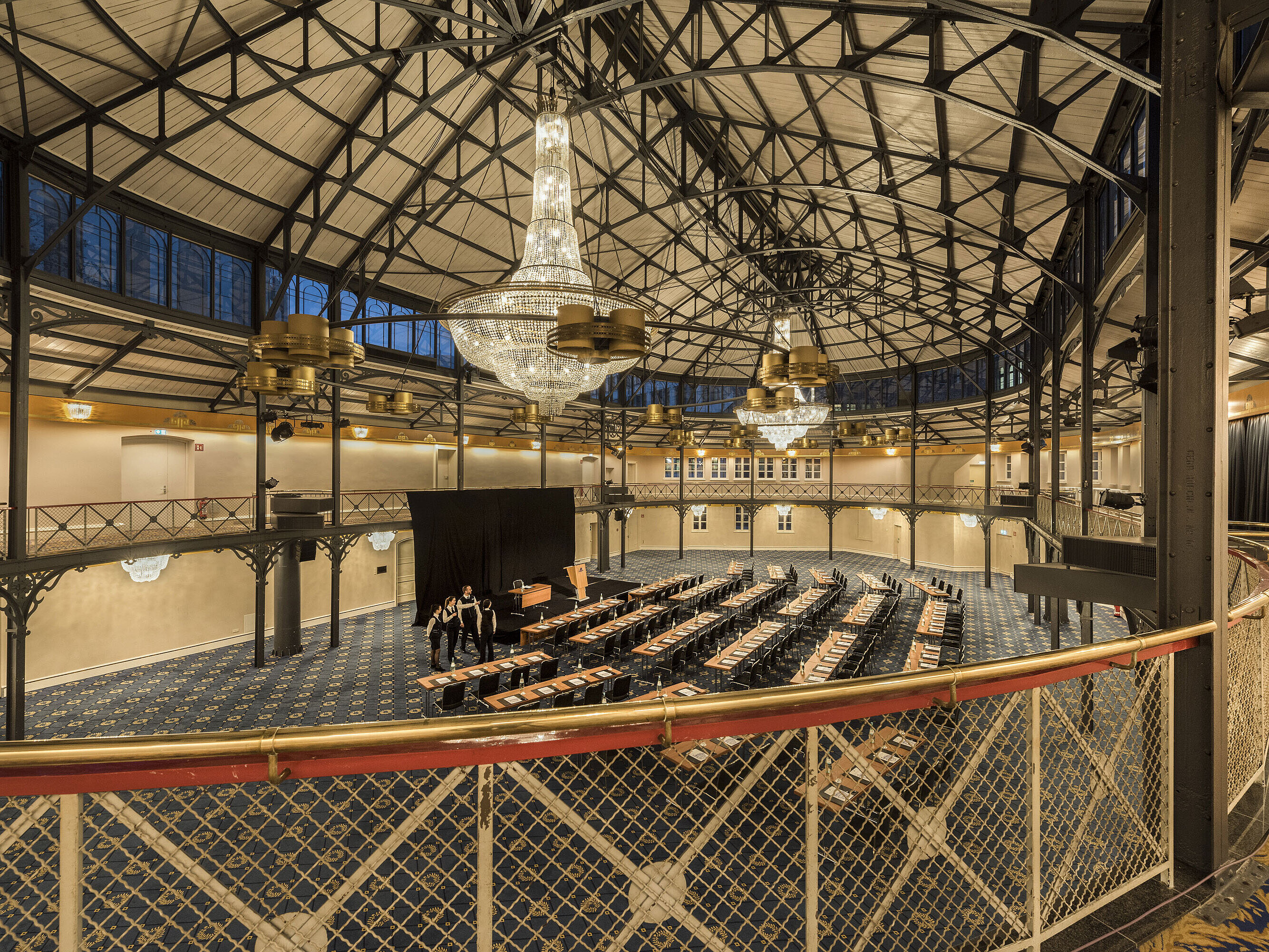 Antigua sala de equitación con escenario, lámparas y sillas en el Maritim Hotel Stuttgart
