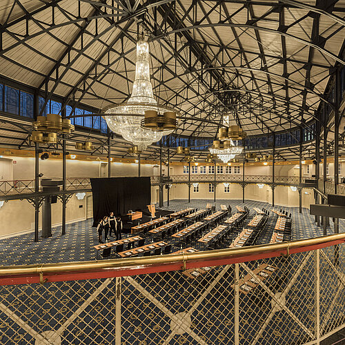Antigua sala de equitación con escenario, lámparas y sillas en el Maritim Hotel Stuttgart