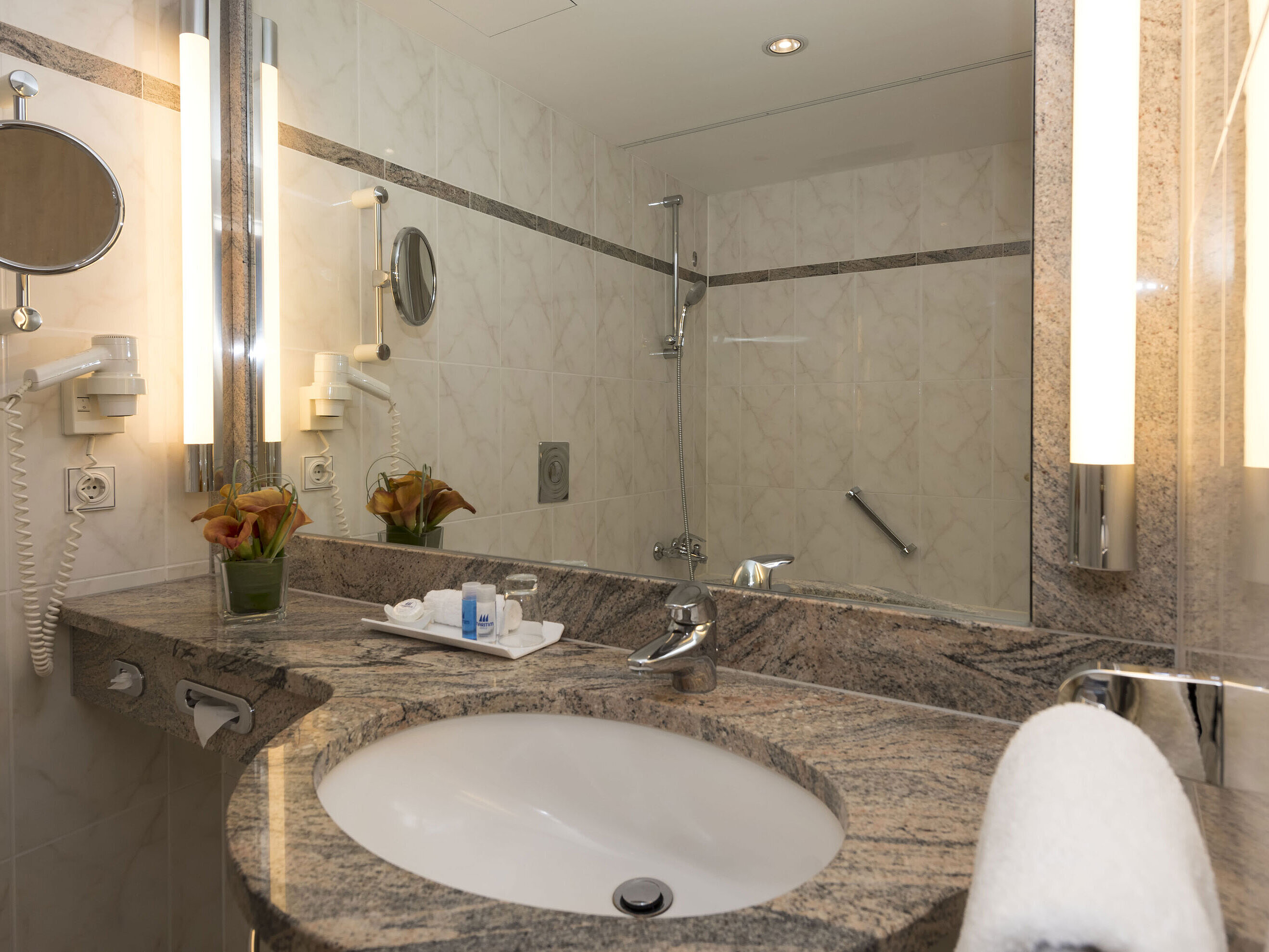 Bagno moderno al Maritim Seehotel Timmendorfer Strand con lavabo in granito, specchio e doccia.