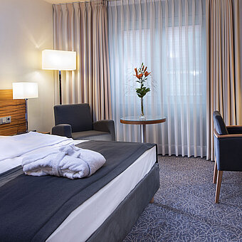 Moderna habitación doble en el Maritim Hotel Múnich. Cómodamente equipada con cama grande, zona de trabajo y sillón.