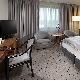 Habitación doble Classic moderna con cama doble acogedora, zona de estar y escritorio en el hotel Maritim Hannover.