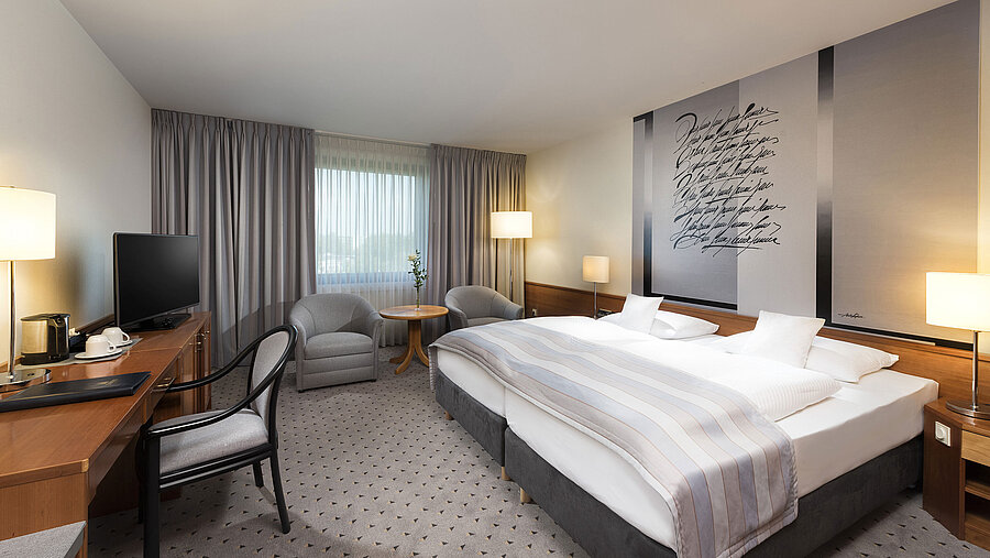 Modern classic double room with a cozy double bed, seating area, and desk at Maritim Hotel Hannover.