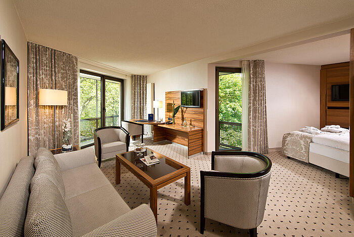 Suite amplia en el Hotel Maritim Bad Homburg con sala de estar separada, balcón y vistas verdes.