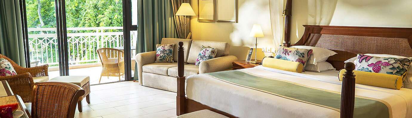 Habitación de hotel amplia con cama con dosel, sofá, balcón y vistas al verde