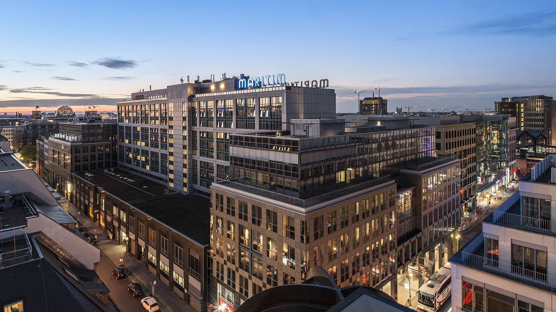 View of Maritim proArte Hotel Berlin at dusk, surrounded by modern buildings in the heart of Berlin.