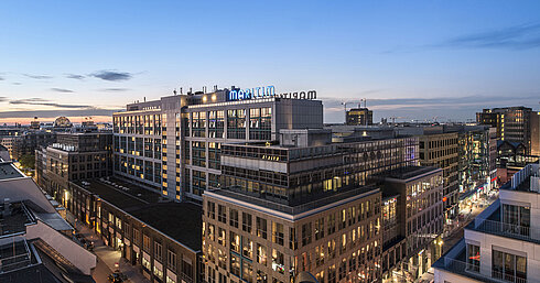 View of Maritim proArte Hotel Berlin at dusk, surrounded by modern buildings in the heart of Berlin.