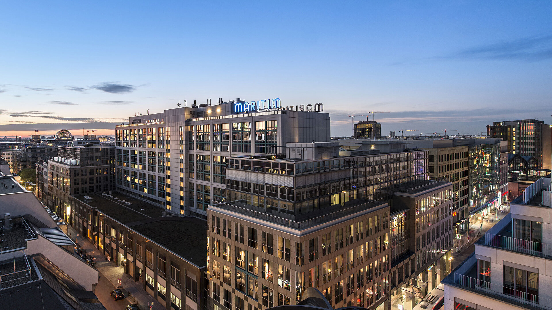 View of Maritim proArte Hotel Berlin at dusk, surrounded by modern buildings in the heart of Berlin.