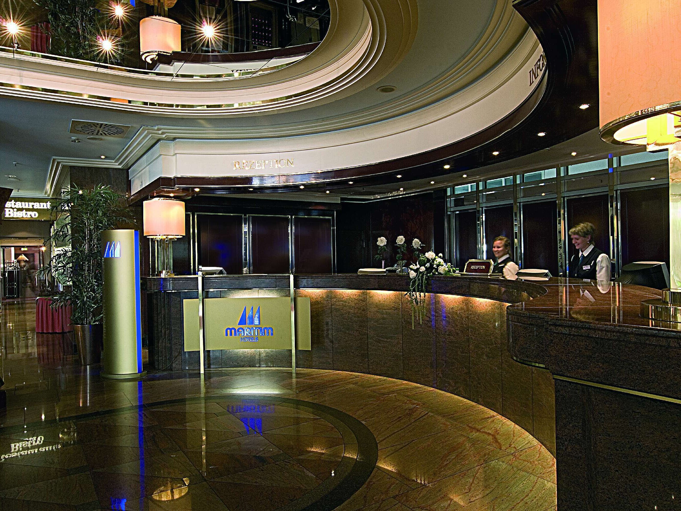 Hall élégant du Maritim Hotel Munich avec réception incurvée, sol en marbre et personnel amical.