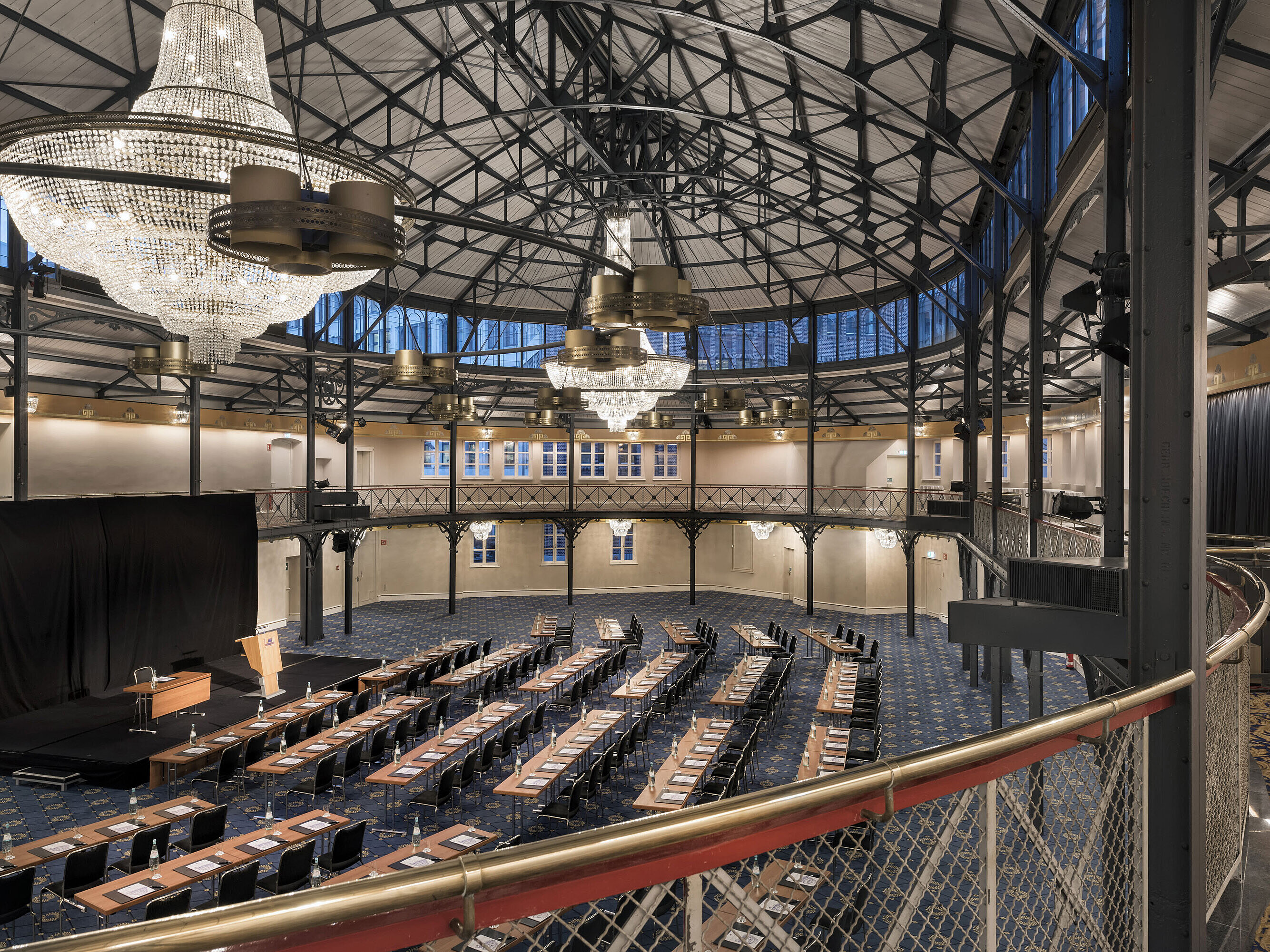 Antigua sala de equitación con escenario, lámparas y sillas en el Maritim Hotel Stuttgart