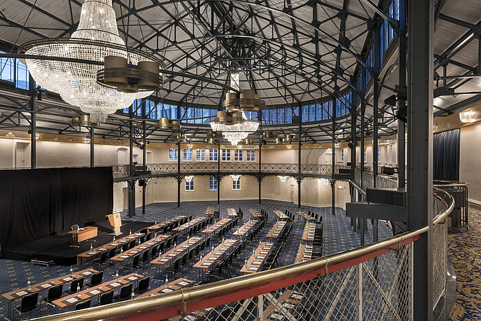 Antigua sala de equitación con escenario, lámparas y sillas en el Maritim Hotel Stuttgart
