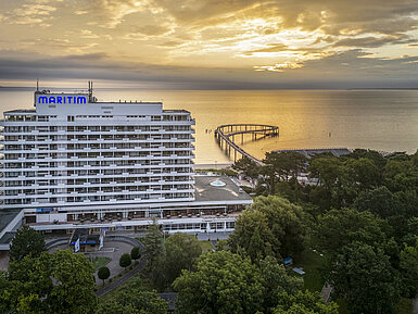 Maritim Seehotel Timmendorfer Strand all’alba con un pontile e vista sul mare.
