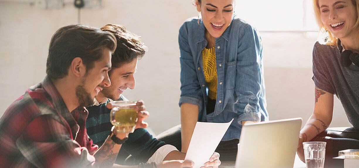 Young colleagues working together on laptop and documents in modern office