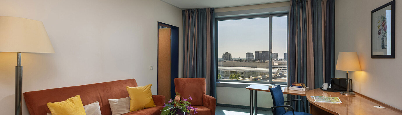Junior Suite at Maritim Hotel Frankfurt with separate living area, sofa, desk, and panoramic city view.