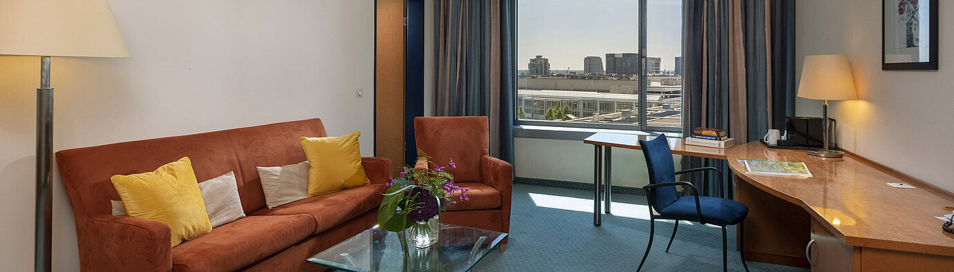 Junior Suite du Maritim Hotel Frankfurt avec salon séparé, canapé, bureau et vue panoramique sur la ville.