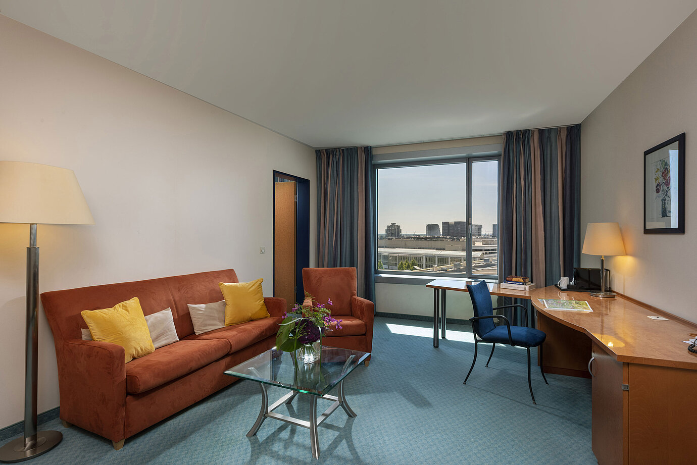 Junior Suite del Maritim Hotel Frankfurt con zona giorno separata, divano, scrivania e vista panoramica sulla città.