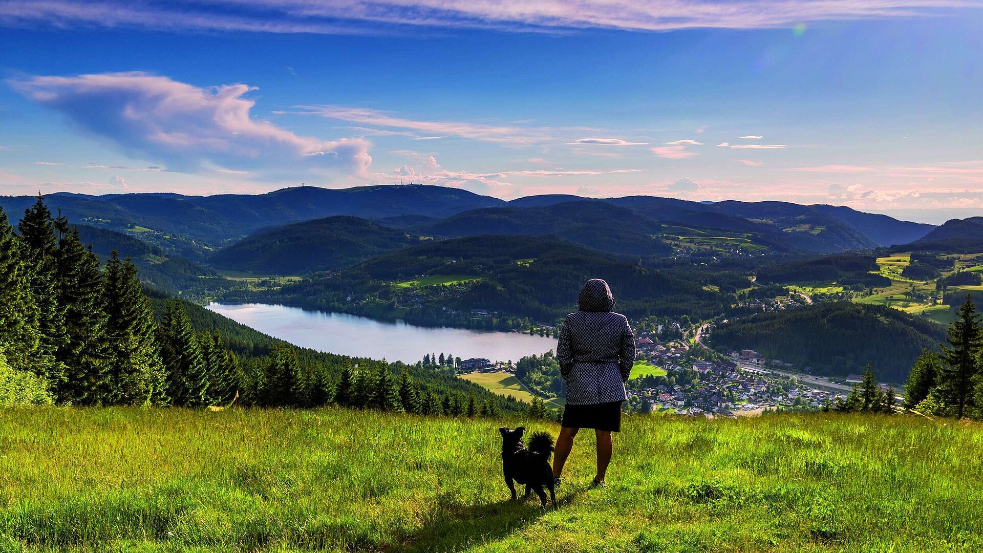 Woman with dog enjoying the view of Lake Titisee and the Black Forest landscape from Hochfirst