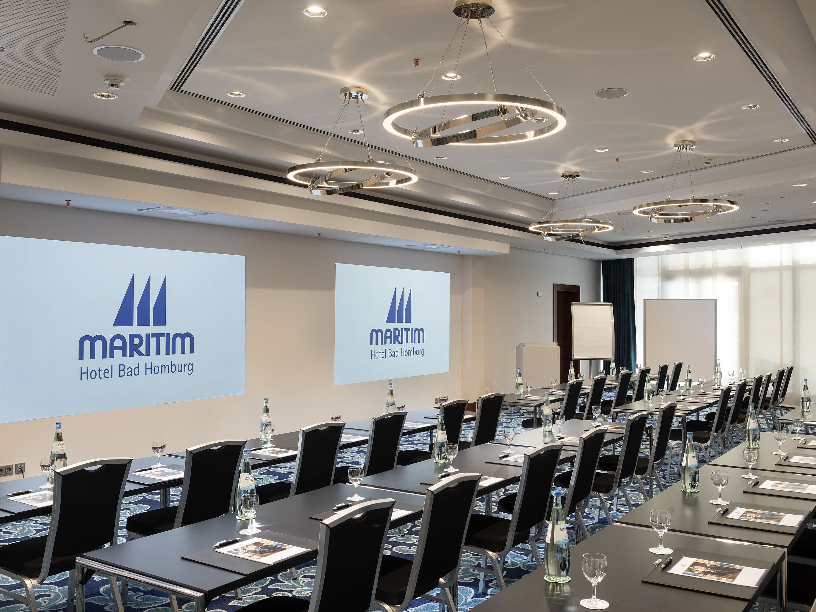 Modern conference room at Maritim Hotel Bad Homburg with seating and projection.