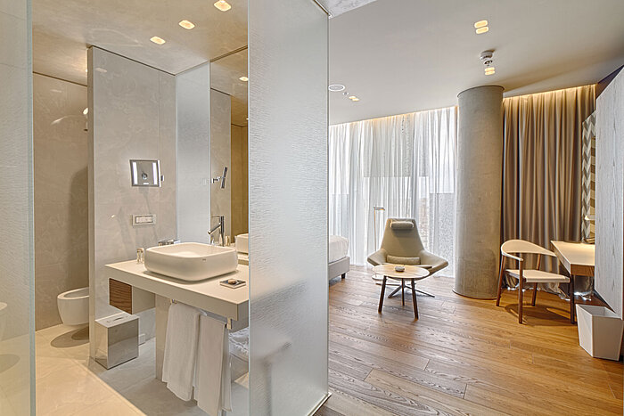 Chambre moderne avec salle de bain ouverte, sol bois et mobilier design au Maritim Hotel Plaza Tirana