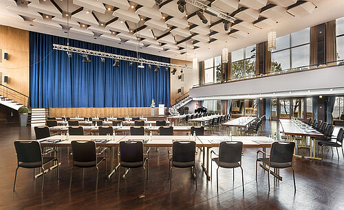 Grande sala „Maritim“ al Maritim Seehotel Timmendorfer Strand con palco, tende blu e sedute per conferenze.
