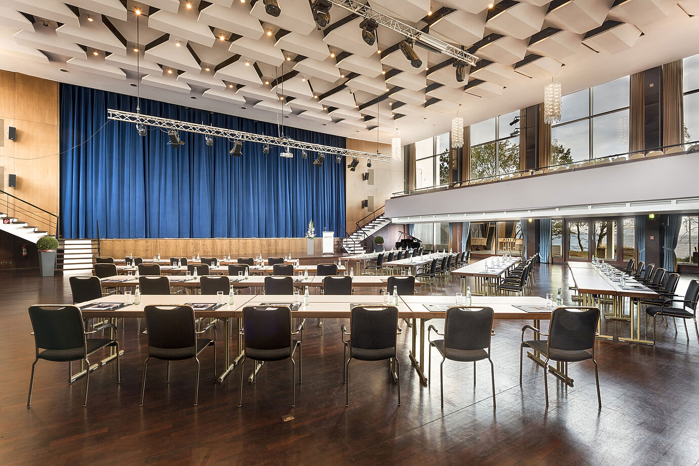 Gran sala «Maritim» en el Maritim Seehotel Timmendorfer Strand con escenario, cortinas azules y asientos para reuniones.