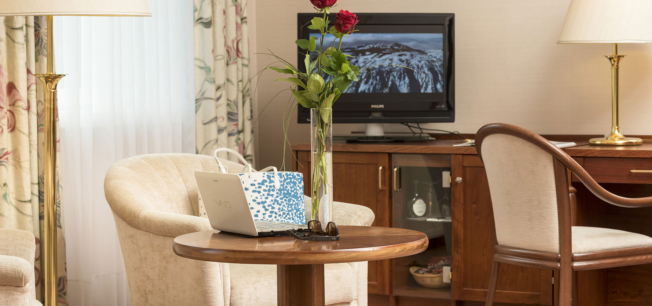Angolo relax con rose, laptop e TV nella camera del Maritim Hotel Bad Wildungen