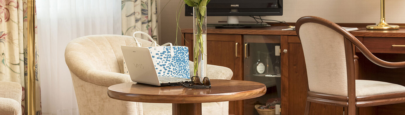 Coin salon avec roses, ordinateur portable et TV dans une chambre du Maritim Hotel Bad Wildungen