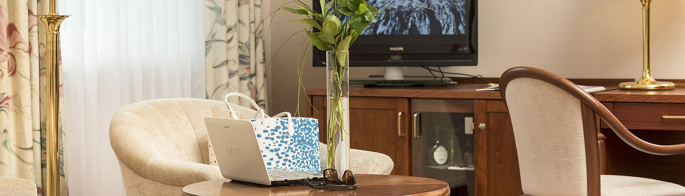 Cosy seating area with roses, laptop and TV in the room of Maritim Hotel Bad Wildungen