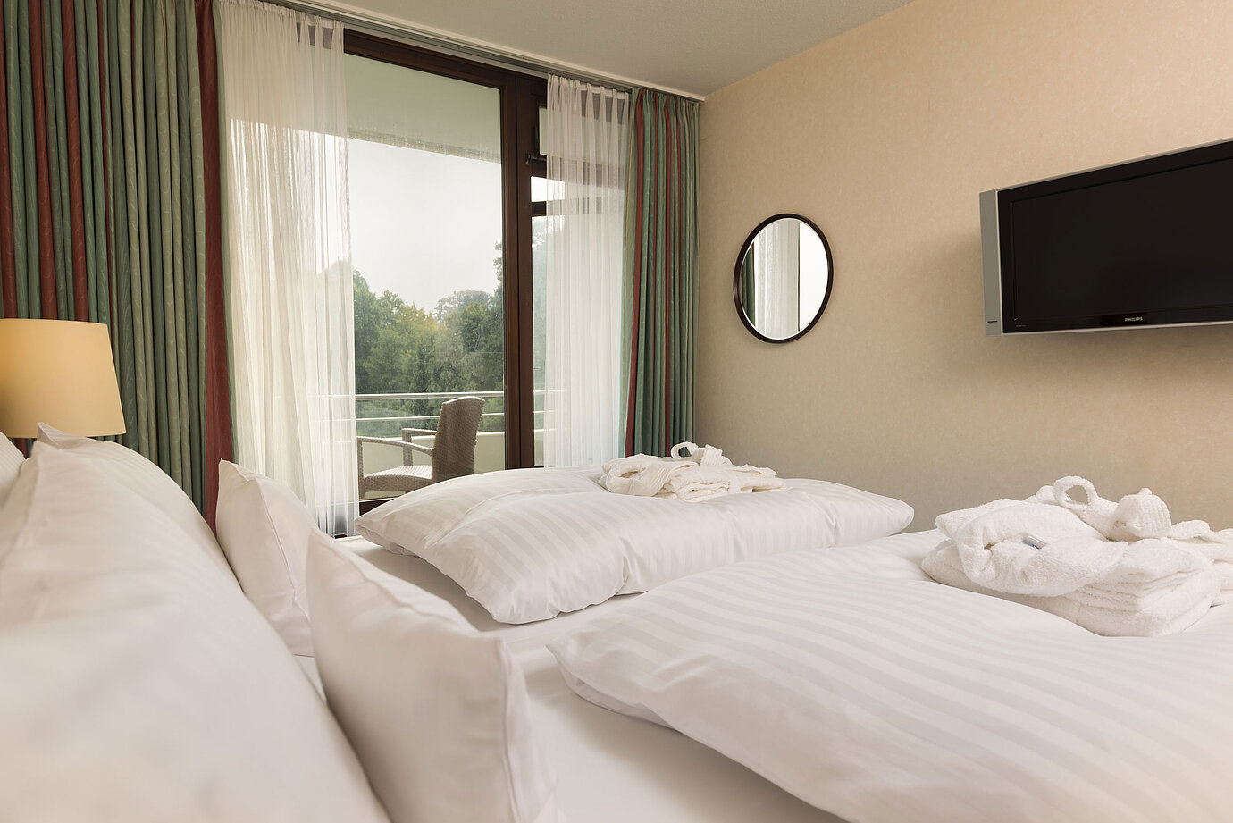 Lit double avec TV, peignoir et vue sur le balcon au Maritim Hotel Bad Salzuflen