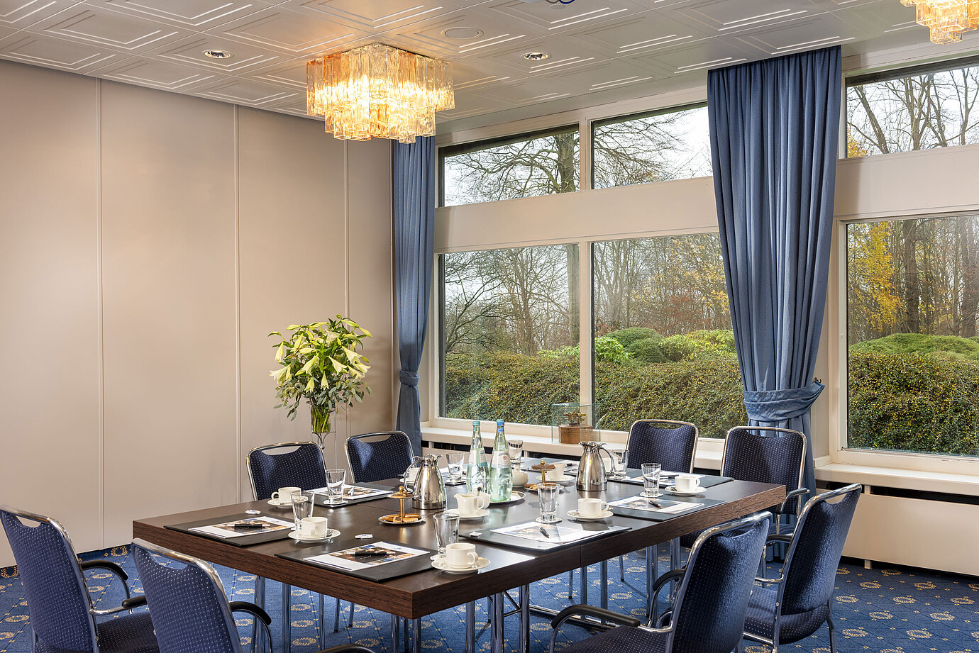 Salón Flensburg en el Maritim Hotel Kiel, sala de conferencias con mesa puesta, grandes ventanales y elegante iluminación.