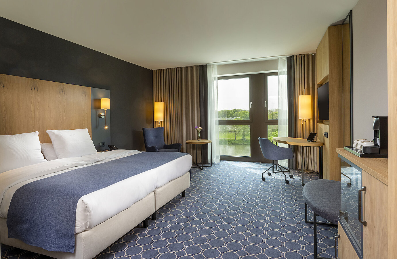 Habitación doble espaciosa en el Maritim Hotel Ingolstadt con cama grande, escritorio y vista al río.