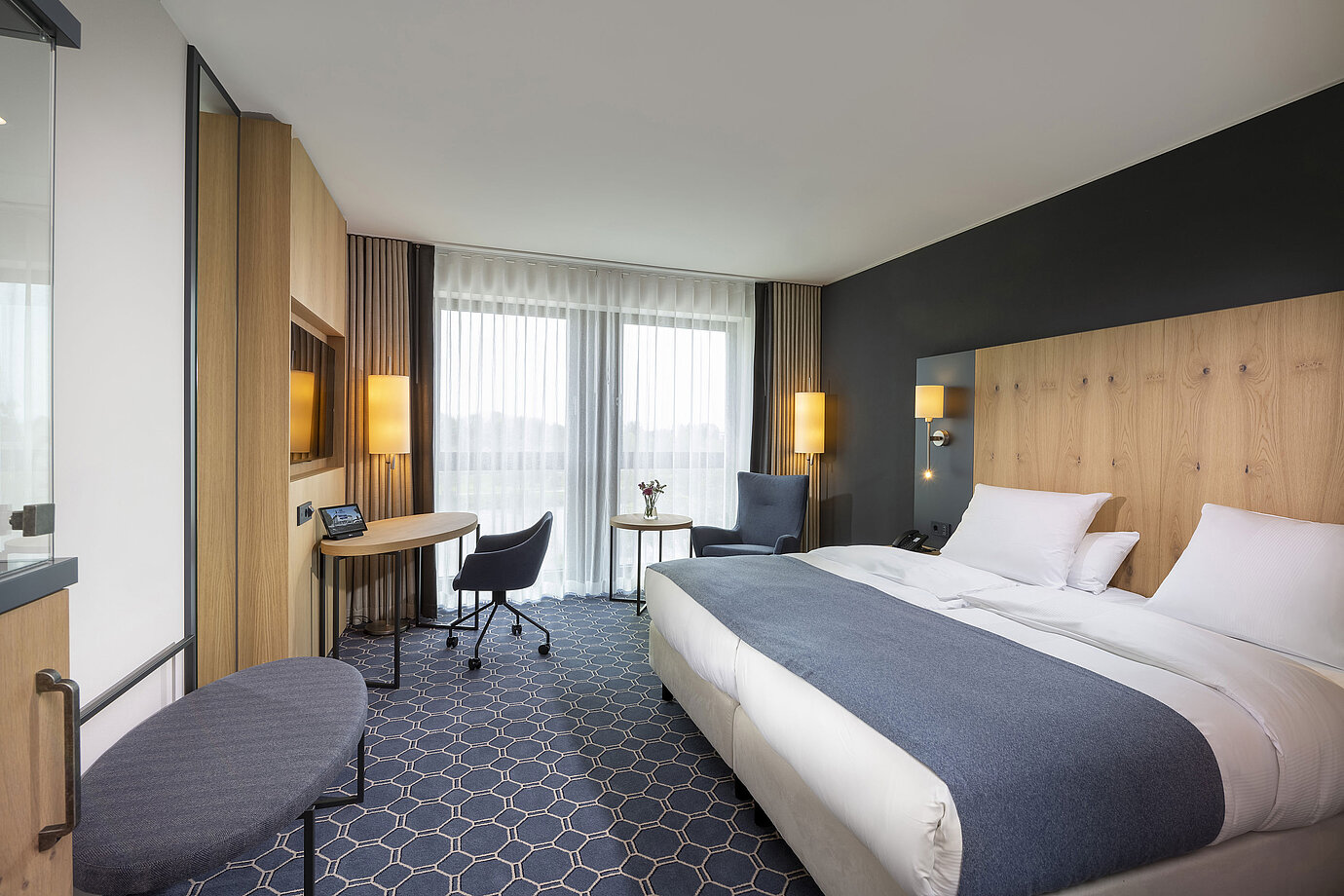 Habitación doble espaciosa en el Maritim Hotel Ingolstadt con escritorio, zona de estar y balcón.