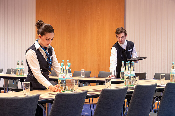 Des collaborateurs préparent une salle de réunion au Maritim Hotel Würzburg pour un événement