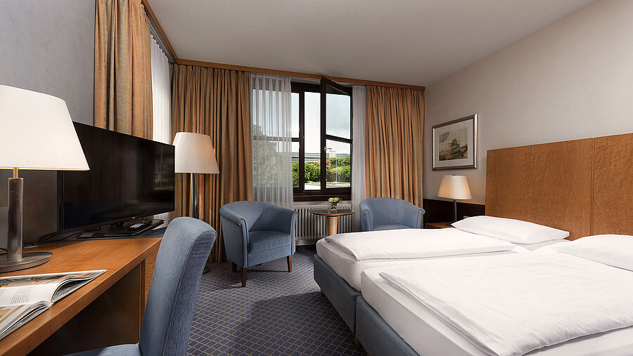 Habitación Classic en Maritim Hotel Fulda con cama doble, escritorio, zona de estar y gran ventana.