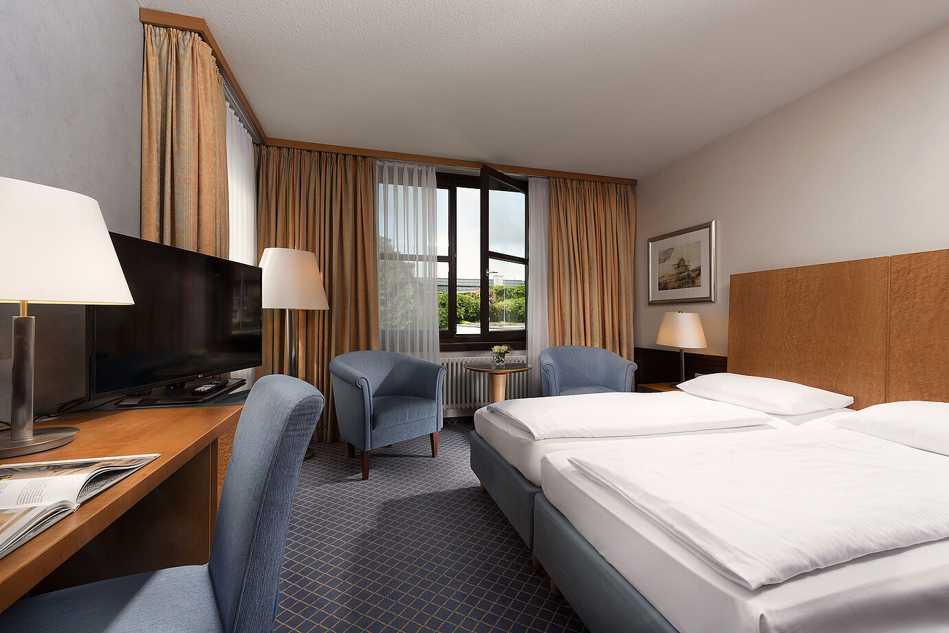 Habitación Classic en Maritim Hotel Fulda con cama doble, escritorio, zona de estar y gran ventana.