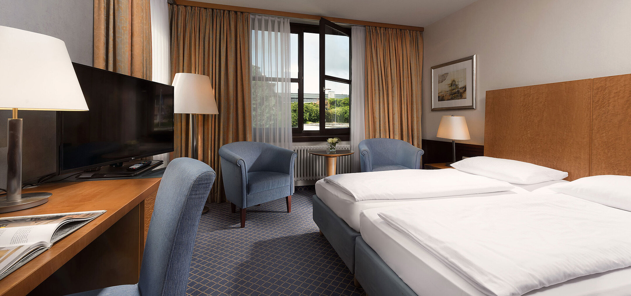Habitación Classic en Maritim Hotel Fulda con cama doble, escritorio, zona de estar y gran ventana.