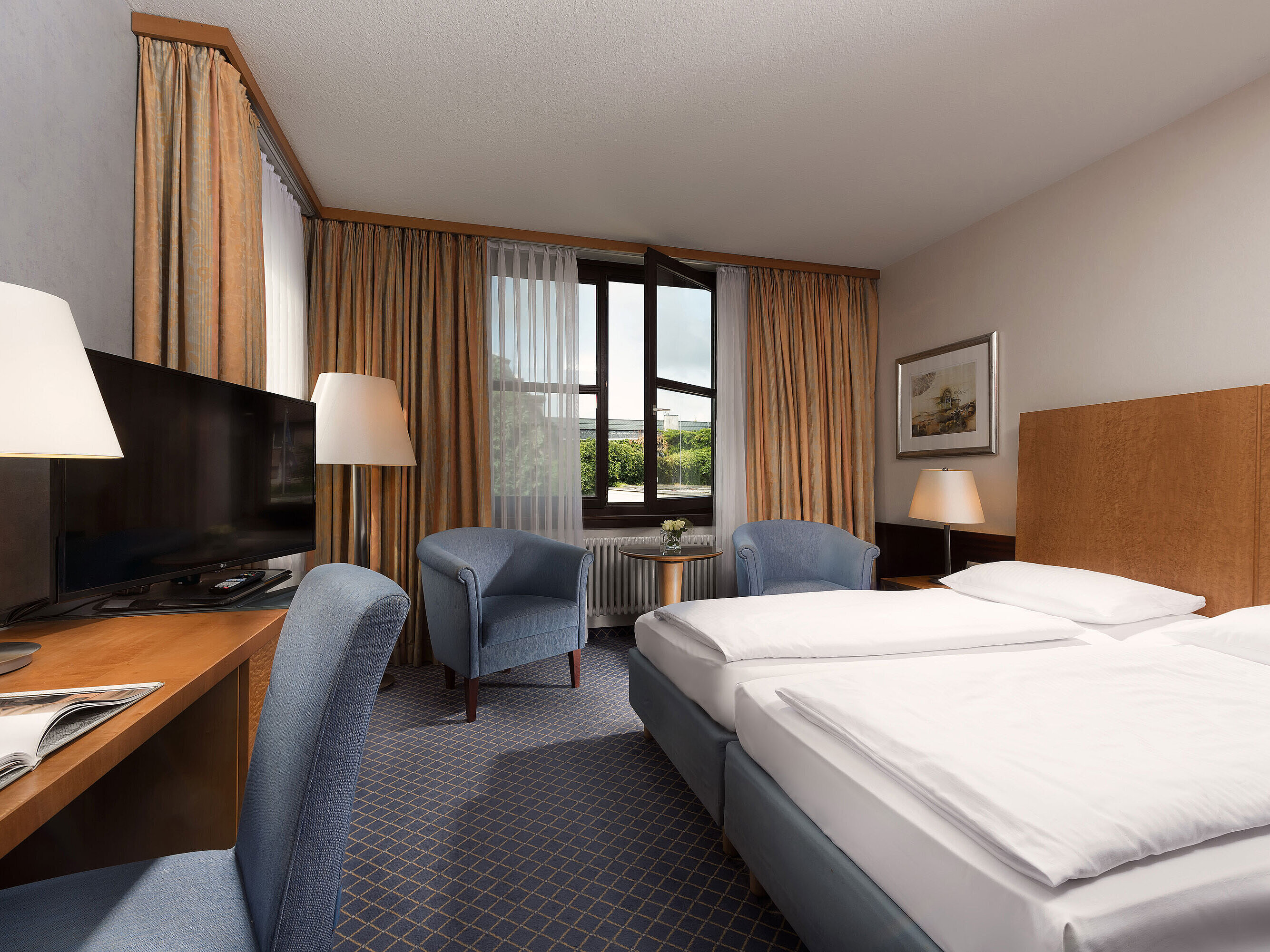 Habitación Classic en Maritim Hotel Fulda con cama doble, escritorio, zona de estar y gran ventana.