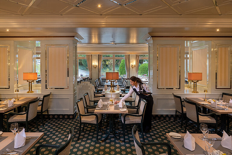 Ristorante Maritim Ristorante elegante con tavoli apparecchiati, ampie finestre e personale che prepara la sala.