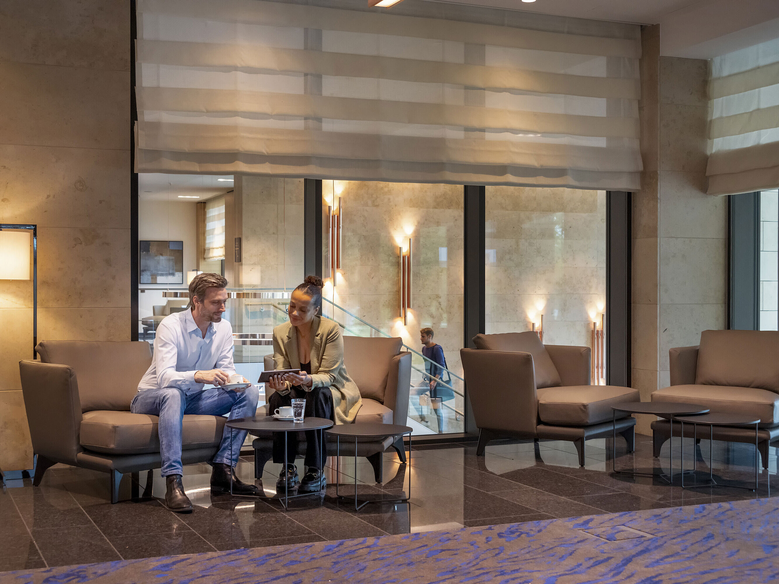 Uomo e donna siedono nella lobby del Maritim Hotel Ingolstadt, chiacchierando davanti a un caffè.