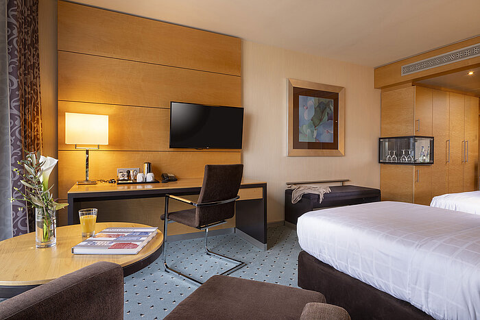 Chambre classique au Maritim Hotel Düsseldorf avec bureau, TV à écran plat, lit double et décoration élégante.